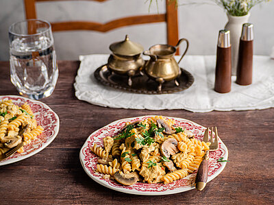 Spirellis mit Pilzen und Tofu auf einem Teller mit Dekoration.