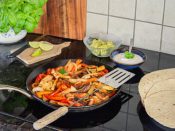 Vegane Tofu-Fajitas Gemüsepfanne mit Tofustreifen auf einem Herd mit Dekoration.