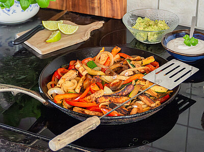 Gemüsepfanne mit Tofustreifen auf einem Herd mit Dekoration.