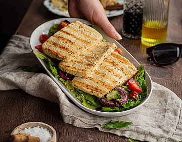 Tofu wie Halloumi 3 gegrillte Tofuscheiben auf Salat in einer Schüssel mit Tischdekoration.