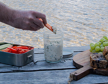 Kräuter-Tofu-Dip mit Gemüsesticks Weißes Kräuterdipp mit Gemüsestreifen auf einem Holztisch und Dekoration.