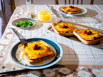 Scheiben Toast, jeweil mit einer Scheibe Tofu, Ananas, Käse und Kirschen belegt mit Tischdekoration.