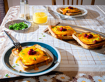 Scheiben Toast, jeweil mit einer Scheibe Tofu, Ananas, Käse und Kirschen belegt mit Tischdekoration.