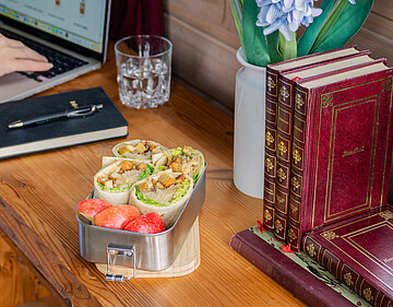 4 Wraps mit Tofu, Sauerkraut und Salat neben einem Apfel in einer Schale  mit Tischdekoration.