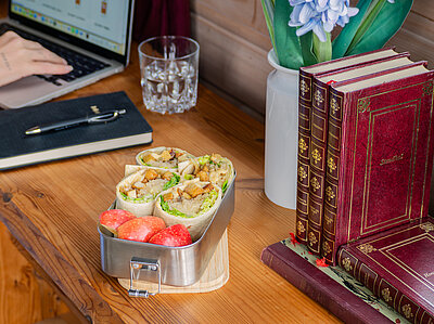 4 Wraps mit Tofu, Sauerkraut und Salat neben einem Apfel in einer Schale  mit Tischdekoration.