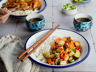 Tofu mit Gemüse und Reis auf Teller mit Dip.