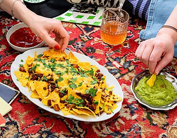 Loaded Nachos Nachos mit Garnitur sowie Guacomole und Dekoration.