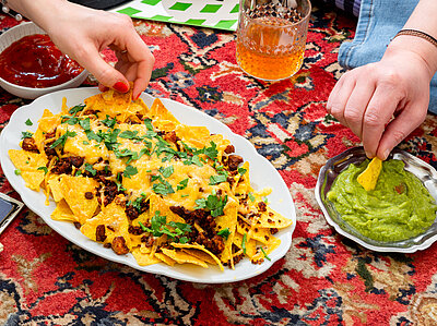 Nachos mit Garnitur sowie Guacomole und Dekoration.