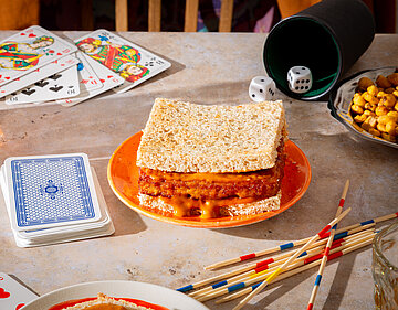 Gochujang Sandwich Sandwich mit Tofu und roter Sauce auf einem Teller mit Tischdekoration.